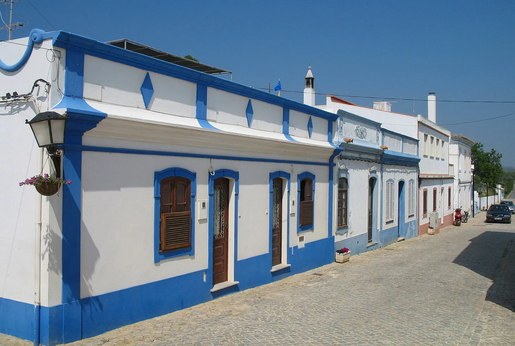 Casas caiadas de branco com barras azuis numa rua de Cacela Velha